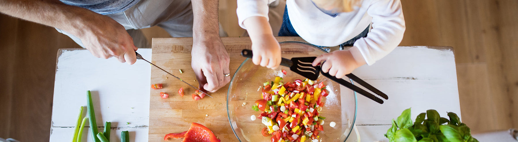 Overhead view of a dad and child cutting up peppers together and making dinner.
