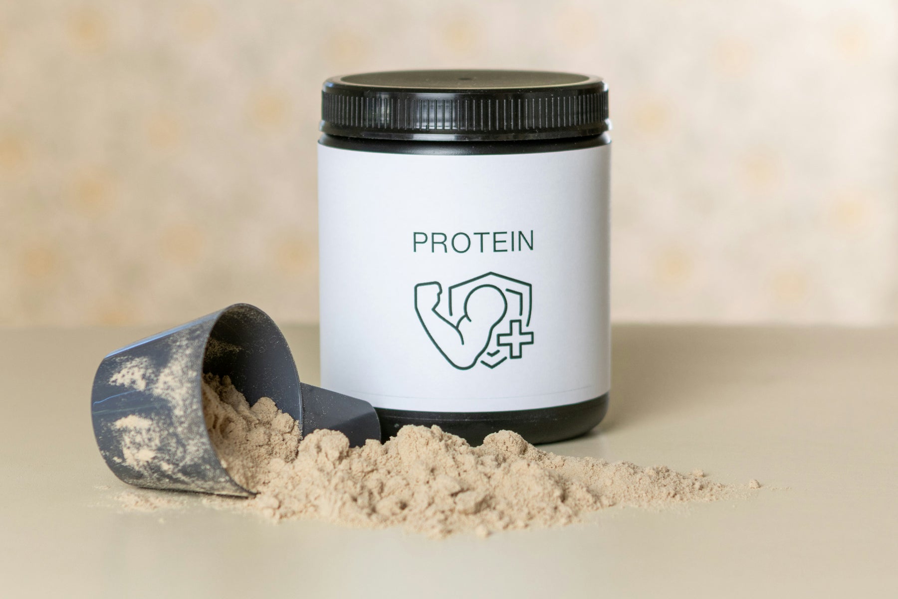 A scoop and spilled protein powder in front of a tub of protein powder with a flexed arm as the logo.