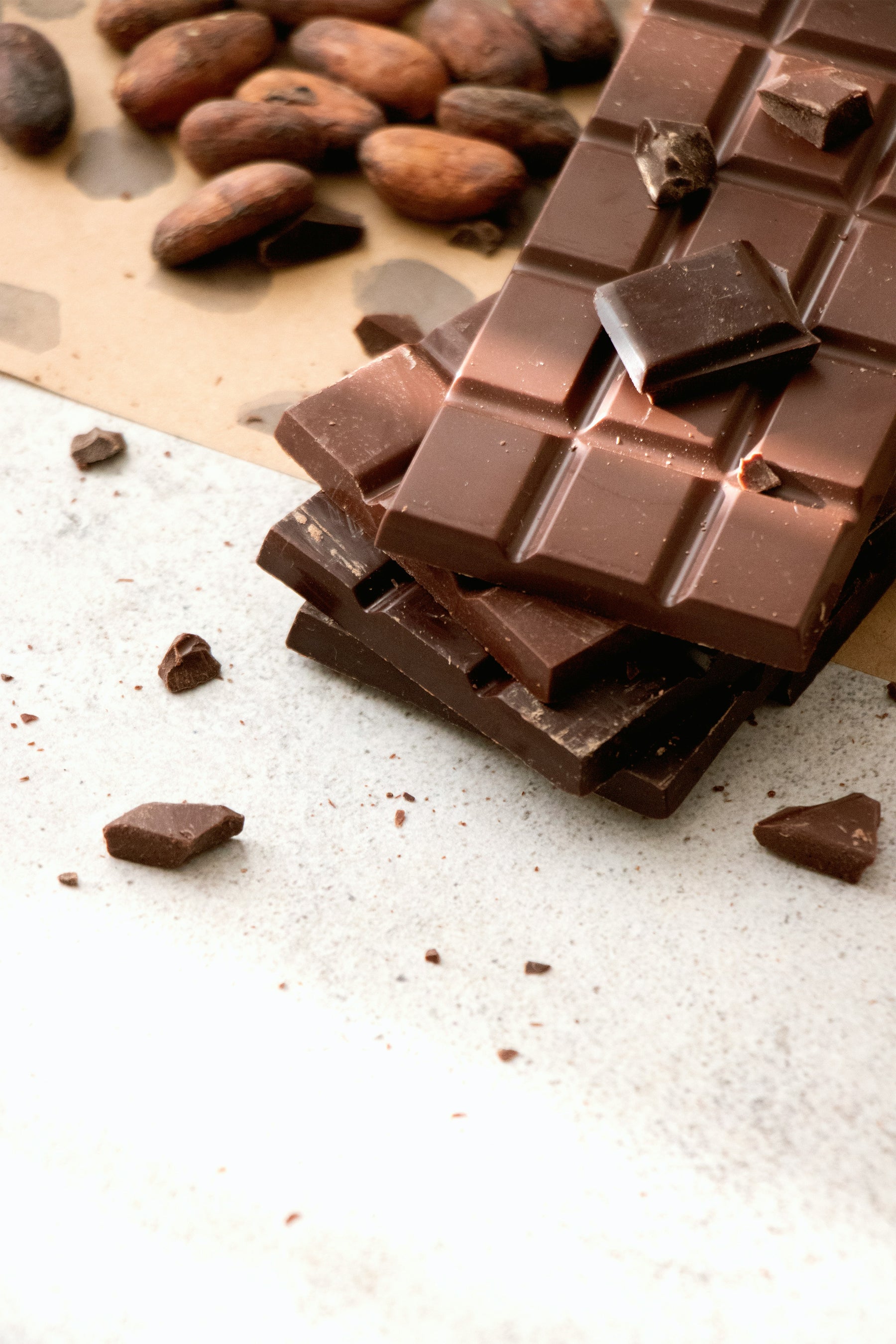 bar of keto dark chocolate laying in front of cocoa beans.