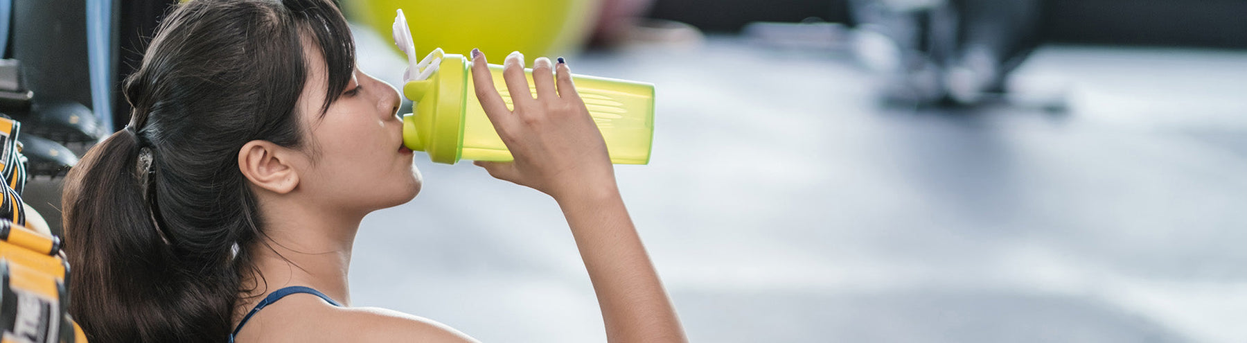 Woman drinking a protein shake at the gym.