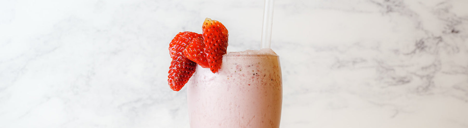 Strawberry meal replacement shake with a straw and fresh strawberries as a garnish.