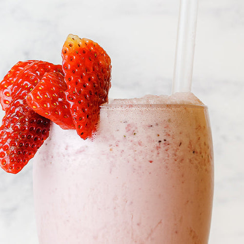 Strawberry meal replacement shake with a straw and fresh strawberries as a garnish.