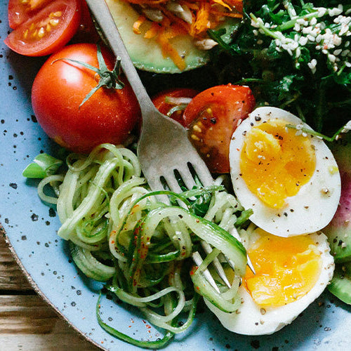 A plate full of healthy food, including a medium boiled egg, tomatoes, and spinach, ideal for a Semaglutide diet.